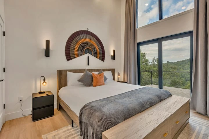 Finished bedroom with tall windows, a timber ceiling, and forest views
