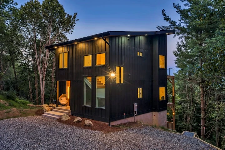 Modern mountain home with illuminated windows at dusk