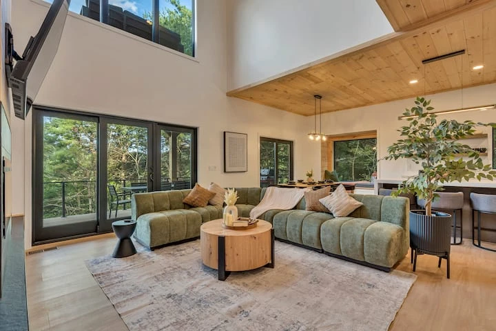 Large black-framed windows bringing forest views into a living room