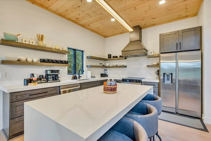 Modern kitchen with a white island, wood cabinetry, and timber ceiling